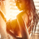 Woman enjoys warm shower water cascading over her breasts in the golden glow from the window behind her ~ MarriageHeat