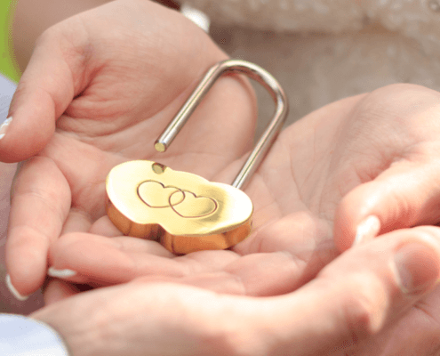 heart-shaped lock open in the cupped palms of a husband and wife - MarriageHeat